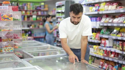 Focused male customer selecting chilled products standing at the fridge in large Stock Footage 341383255