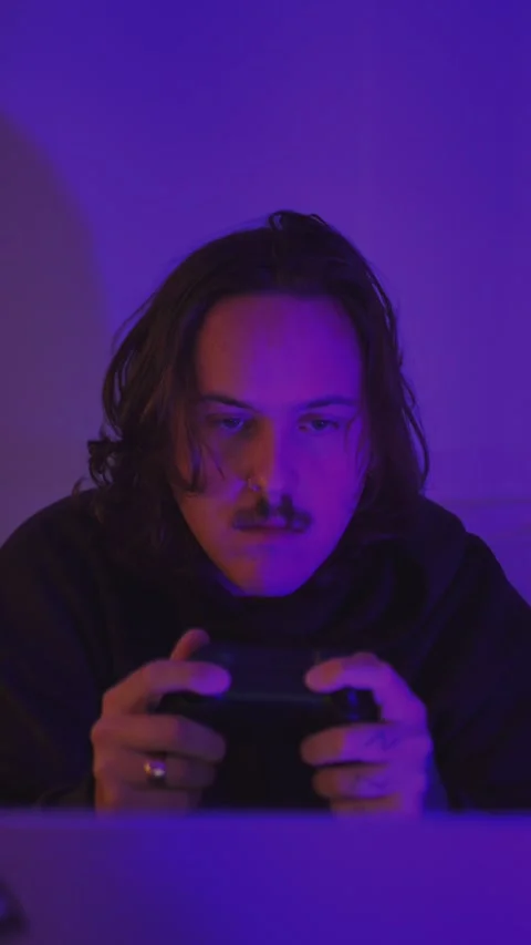 Focused male gamer holding a controller in purple neon bedroom... Vídeo Stock 337968360