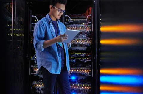Focused male IT technician using digital tablet at panel in dark server room Foto stock