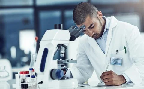 Focused male lab technician using digital tablet working on medical development Stockfoto's