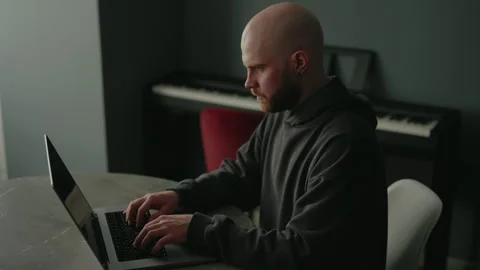 Focused male programmer with beard wearing dark hoodie remote working from home Stock Footage 305503999