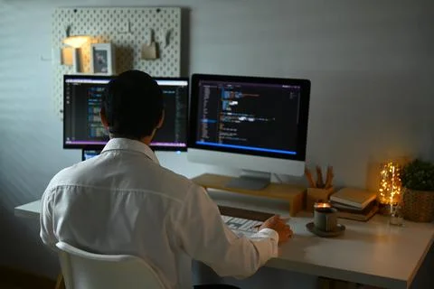 Focused male programmer working with coded data on computer screen at dark room Stock Photos