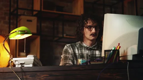 Focused male programmer working on computer in vintage office late at night Stock Footage 321072548