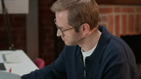 Focused Male Programmer Working on Laptop and Taking Notes in Office Video stock 319993224