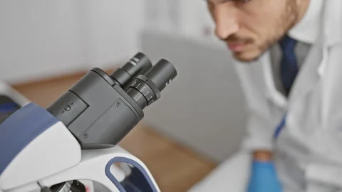 A focused male scientist uses a microscope in a laboratory, suggesting rese.. Stock Footage 267200925