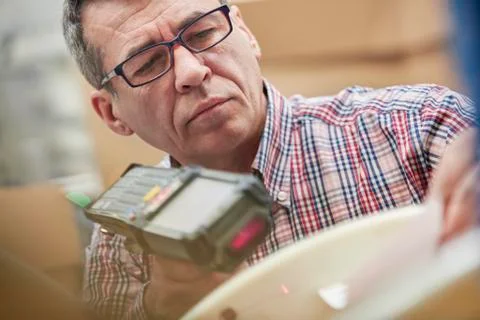 Focused male worker using IR code scanner in fiber optics warehouse Stock-Fotos