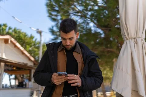 Focused man checking messages on cellphone in outdoor cafe Stock Photos