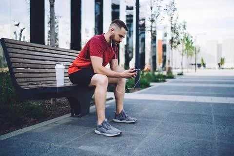 Focused man checking smartphone while sitting on bench Stock Photos