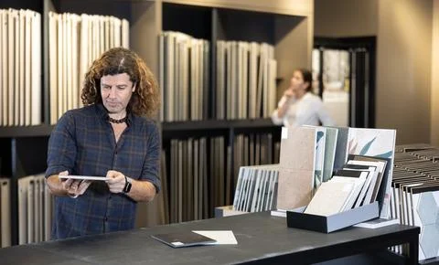Focused man choosing wall tiling materials in hardware shop Foto stock