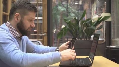Focused man copying data from smartphone to laptop, in cafe, profile, steadicam 動画素材 73072711