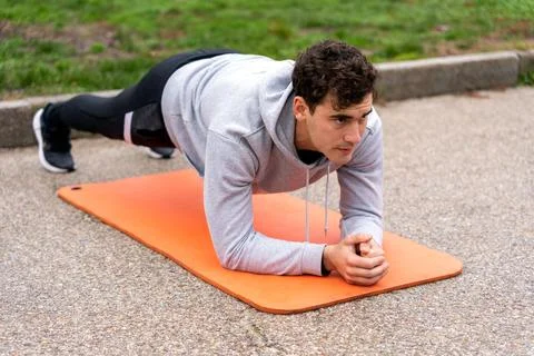 Focused man doing plank in park Stock Photos