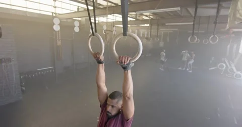 Focused man doing pull ups on gym rings at gym, in slow motion Stock Footage 342111114