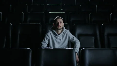 A focused man drinks coffee and enthusiastically watches a movie at the cinema Stock Footage 232940333