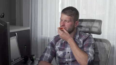 Focused man enjoying pizza while brainstorming on his computer Stock Footage 311919742