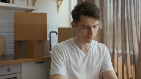 Focused man finishes report on laptop at kitchen table Vidéo 201167478