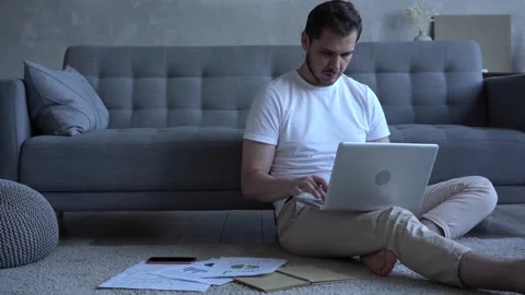 Focused man freelancer sitting on floor in cozy living room using computer Stock Footage 137955662