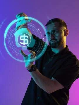 Focused man holding digital dollar icon in glowing financial HUD interface Stock Photos