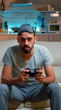 Focused man holding joystick while sitting in front of television Stock Photos
