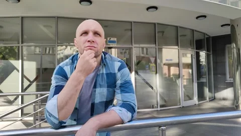 Focused man leans on railing and rubs his chin Stockbeeldmateriaal 201636009