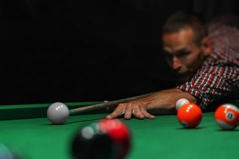 A focused man is lining up a shot in a game of billiards on a green felt table Stock Photos
