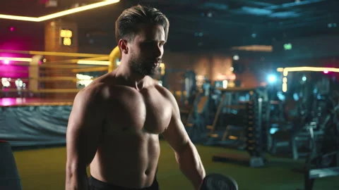 Focused Man Performing Bicep Curls with Dumbbells in a Gym Stock Footage 270243432