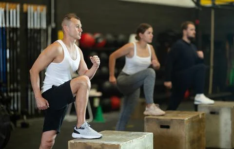Focused man performing step-ups on box in functional training session 스톡 사진