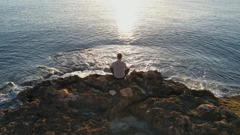 Focused man practicing meditation on a rocky beach summer morning. Yoga man.. Stock Footage 233543127