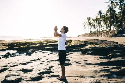 Focused man preparing to do Raised Arms pose at coast Stock Photos