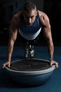 Focused man with prosthesis training on ball Stock-Fotos