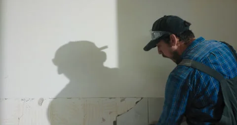 A focused man puts all strength while hammering tiles in kitchen bathroom. A man Stock Footage 215755385