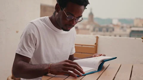 Focused Man Reading Book On Urban Balcony Stock Footage 329935067