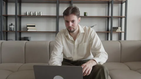 Focused Man Sitting on Sofa with Laptop, Celebrating Good News from an Email Stock Footage 301243716