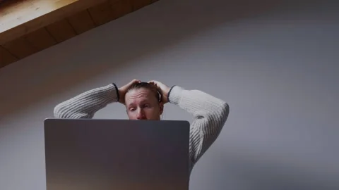 Focused man solving problem while working on laptop at home Video stock 334735956