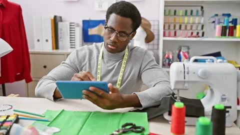 Focused man tailor using tablet in a well-equipped atelier with colorful th.. Stock Footage 276175732