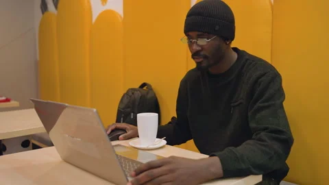 Focused man types in bright booth. Individual engages with laptop in cheerful Stock Footage 338286468