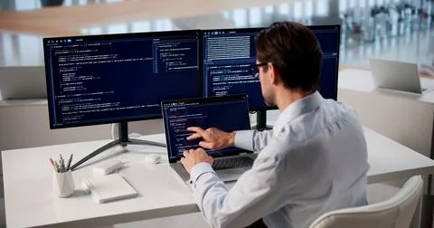 Focused Man Typing Code On Laptop At Modern Office Workspace. Stock Photos