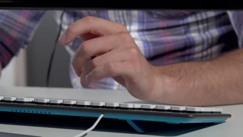 Focused man typing energetically on a sleek computer keyboard Stock Footage 311542852