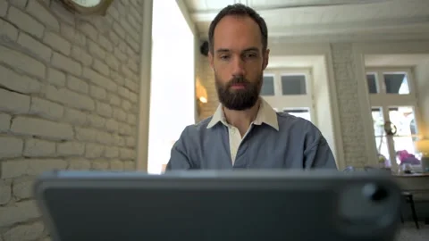 Focused man typing on a tablet at a desk Stock Footage 308636591