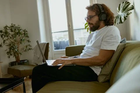 Focused man using laptop for online learning or watching movie while lying on Foto stock