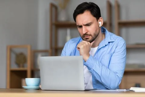 Focused Man Using Laptop for Work During Daytime in Office 写真素材