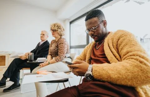 Focused man using smart phone during business workshop with colleagues. Stock Photos
