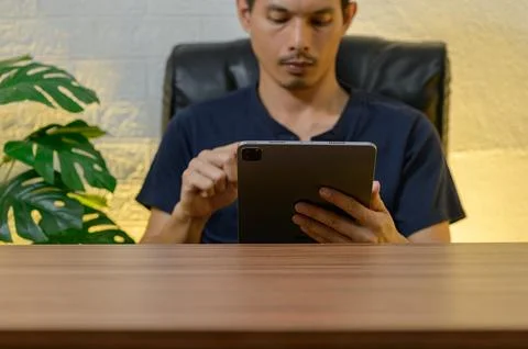 Focused Man Using Tablet in Modern Workspace with Indoor Plants Stock Photos