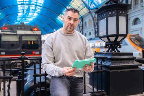Focused Man Using Tablet While Waiting at Train Station looking at camera Stock Photos