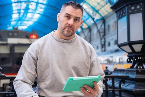 Focused Man Using Tablet While Waiting at Train Station Stock Photos