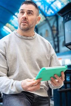 Focused Man Using Tablet While Waiting at Train Station looking at camera Stock Photos