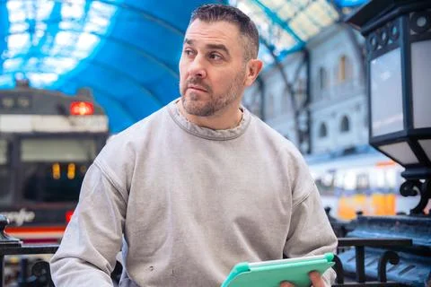 Focused Man Using Tablet While Waiting at Train Station looking at camera Stock Photos