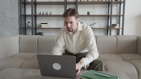 Focused Man Working On Laptop And Typing While Sitting On Sofa At Home Video stock 331793058