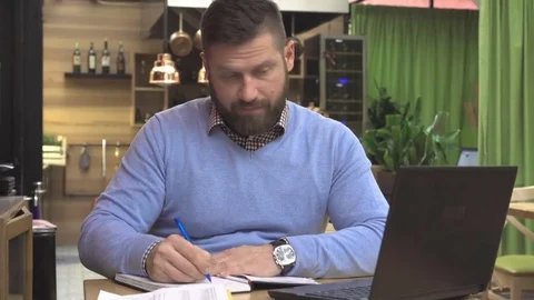 Focused man working with laptop computer and notes in calendar, pub, steadicam Vidéo 73068654