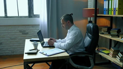 Focused man working with a laptop at a desk in the office. Stock Footage 133444772