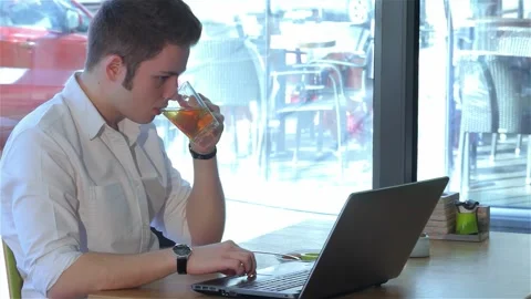 Focused man working on laptop while enjoying tea at a cozy cafe Video stock 311542795